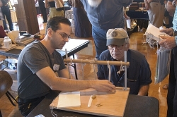 Ben Colborn demonstrates sewing over tapes, a book binding method using a sewing frame