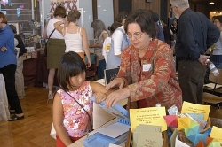 Artist Virginia Dunstan shows a young visitor how to use the Riso Print Gocco screen printer Artist Virginia Dunstan shows a young visitor how to use the Riso Print Gocco screen printer